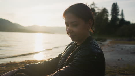 woman sitting by a lake at sunset