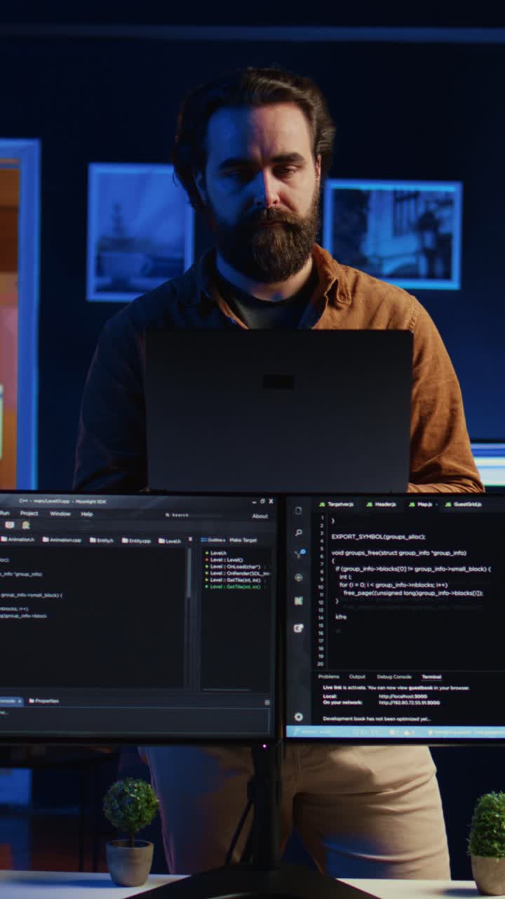 Focused Programmer Working on Laptop and Multiple Screens at Night