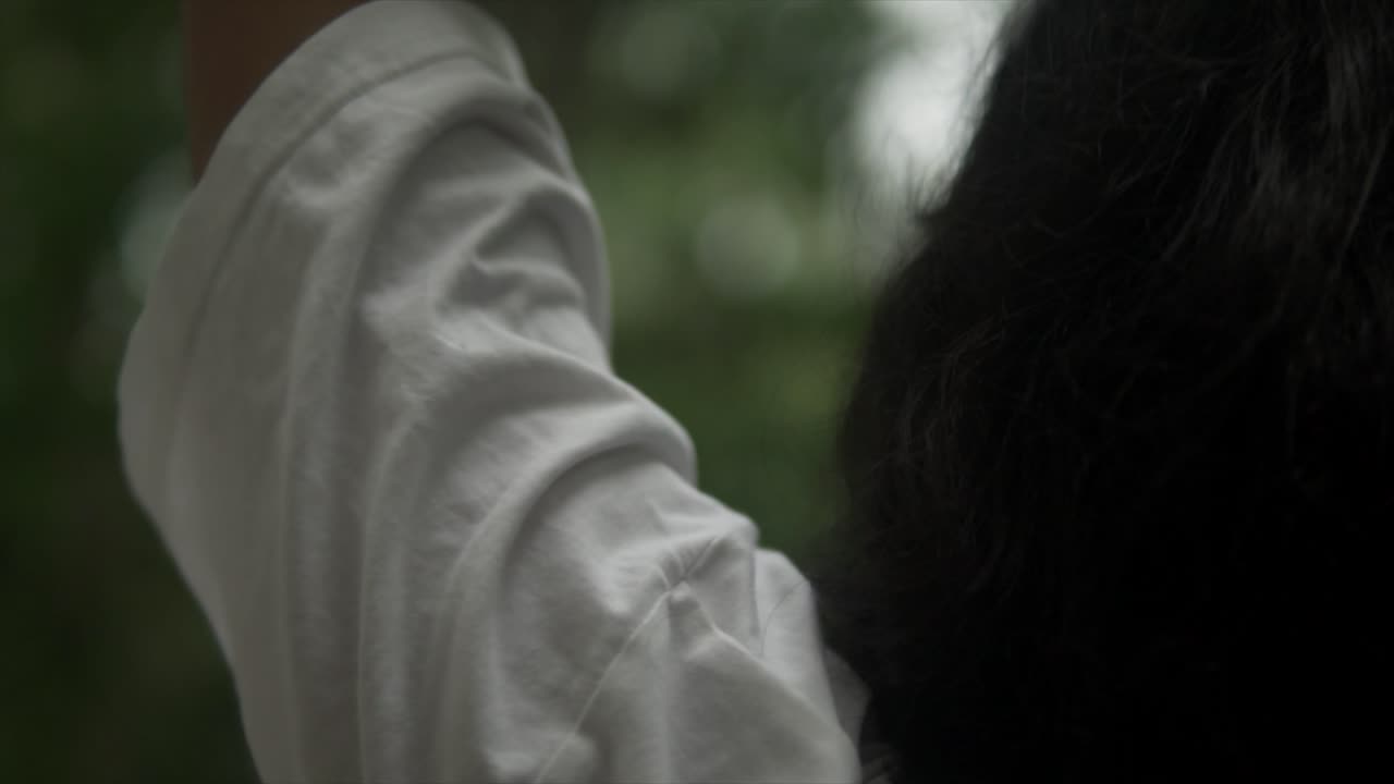 여자는 머리 위에 팔을 들고, 팔과 머리 사이의 공간을 향해 천천히 돌리