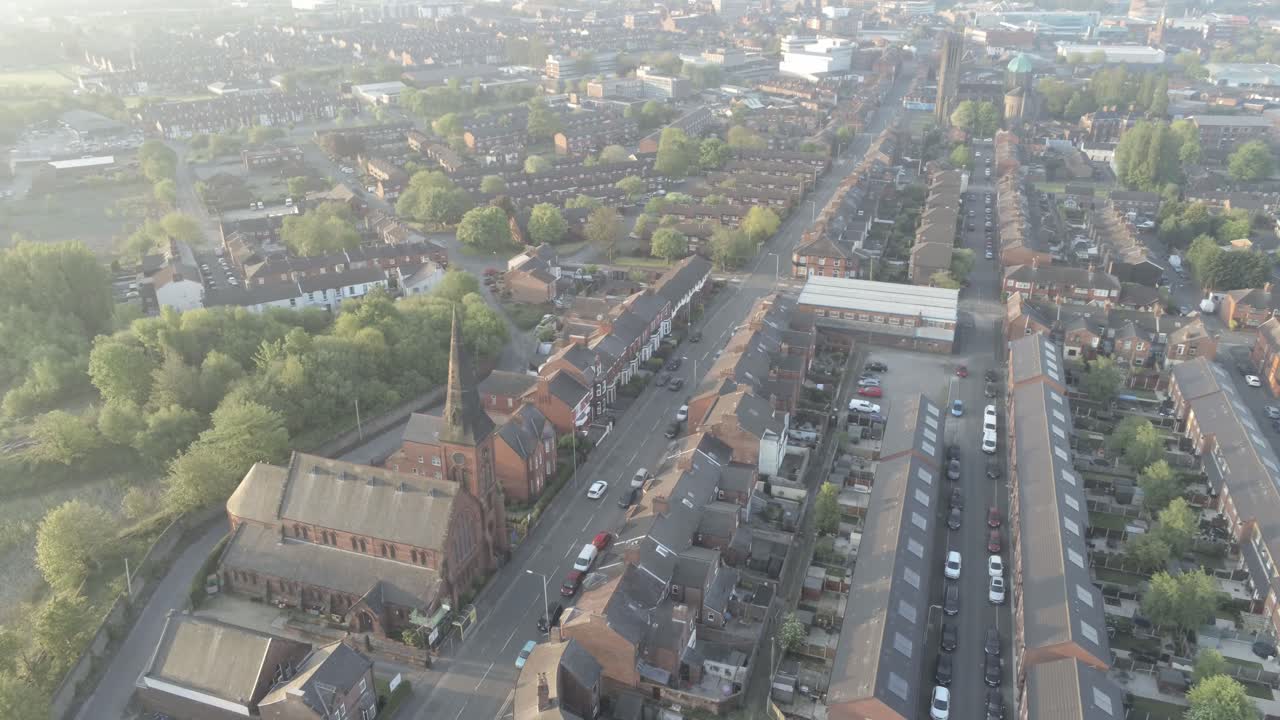 vista de drones descendiendo a casas de ciudad británicas - iglesia con campanario al amanecer mientras los autos conducen por un largo camino
