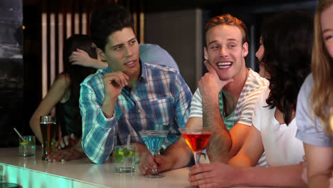 Attractive-friends-talking-and-drinking-at-the-bar