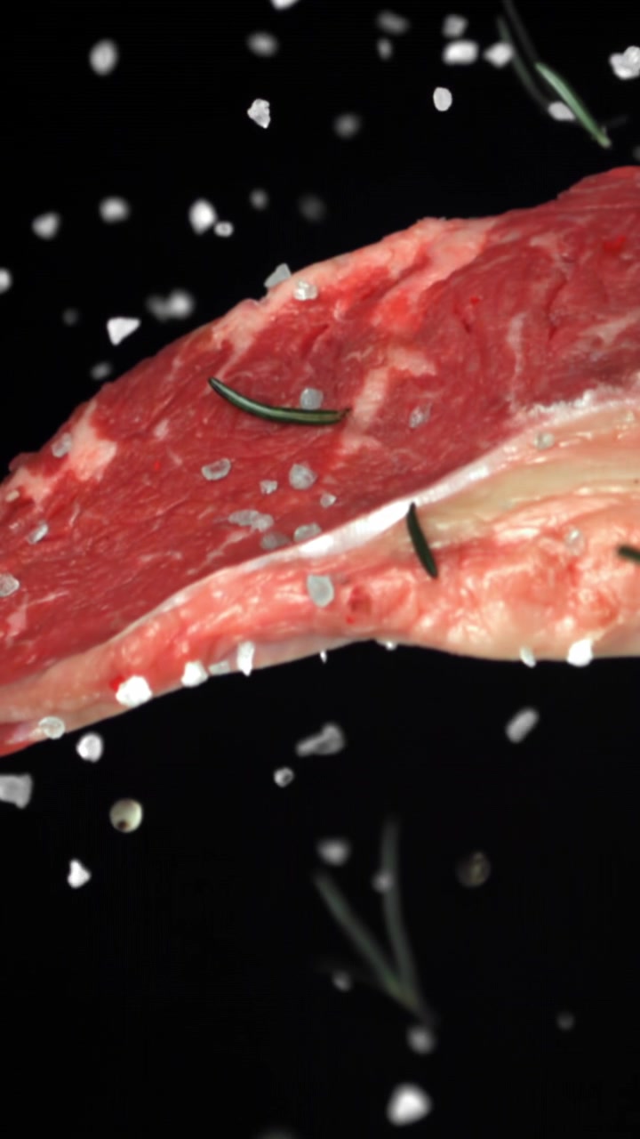 Raw Beef Steak Seasoned with Salt and Rosemary in Slow Motion