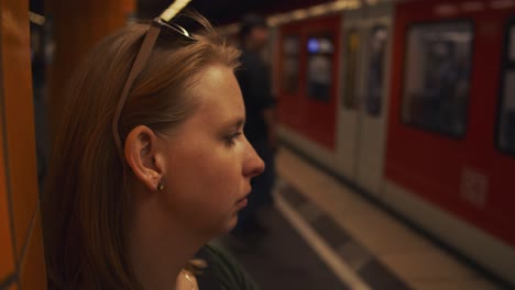 el tren llega mientras una mujer espera en el andén.