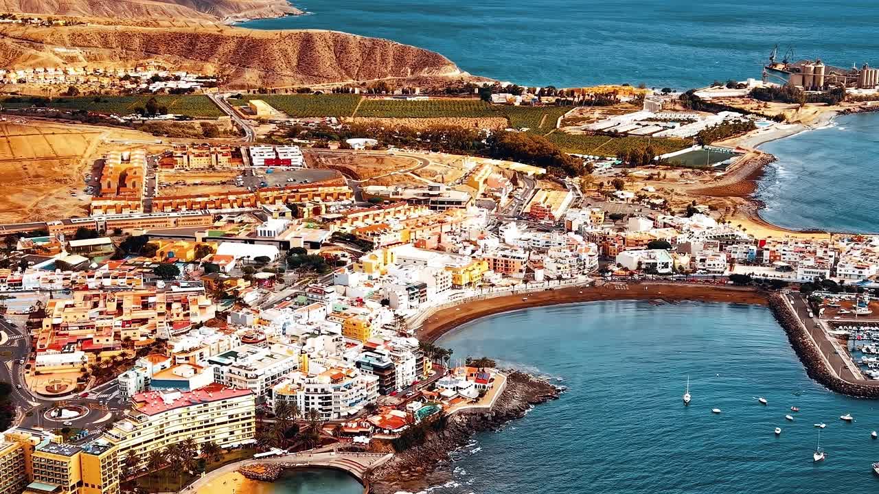 Luftfoto af Gran Canarias kystlinje viser by og hav i dagtimerne.