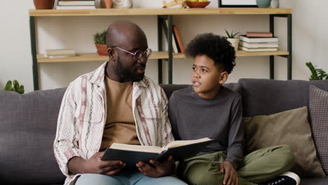 father and son reading in the sofa