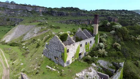 Abandoned-overgrown-ivy-covered-desolate-countryside-historical-Welsh-coastal-brick-factory-mill-aerial-view-push-in-slow