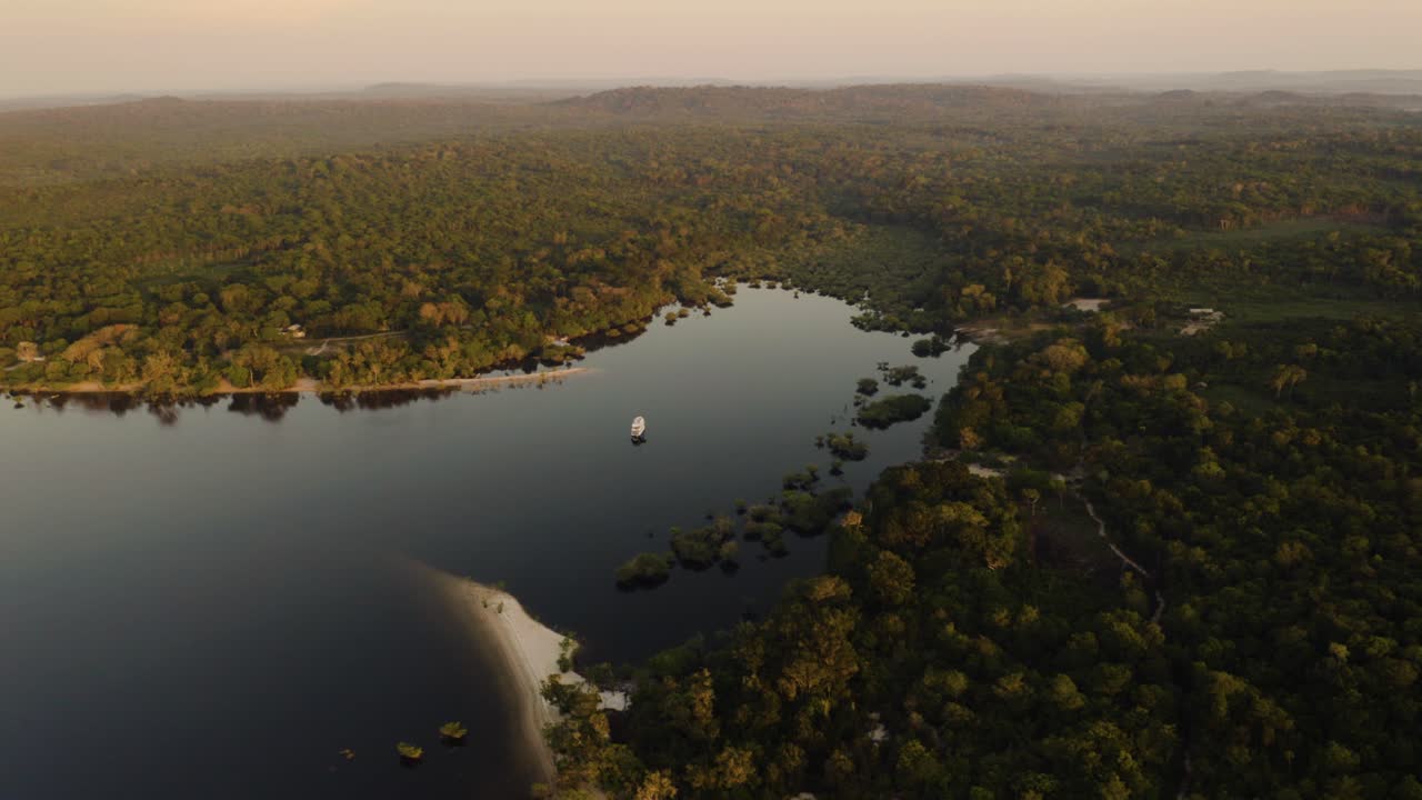 A yacht sits in a sheltered peaceful lagoon in the Amazon rainforest at sunrise