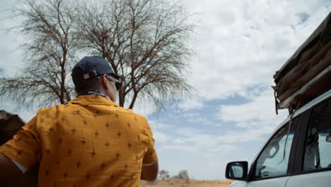 hand held shot of a off-roading caucasian male taking out a rooftop tent cover and throwing it onto the roof of the vehicle