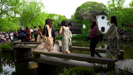 chinese tourists cross a zigzag bridge in humble administrator's garden of suzhou, china