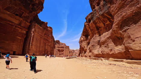 spectacular scenery of rock-cut facades in petra, jordan, west asia. low angle view at the famous landmark. multiple people walks by the landmark.