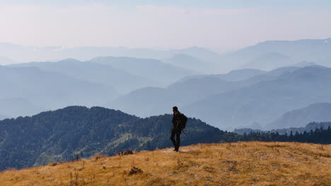 Ein-Männlicher-Tourist-Spaziert-Durch-Die-Hügelige-Bergkette-Am-Nepalesischen-Pikeypeak-Und-Genießt-Das-Landschaftsszenario-Einer-Drohnenaufnahme-In-4K