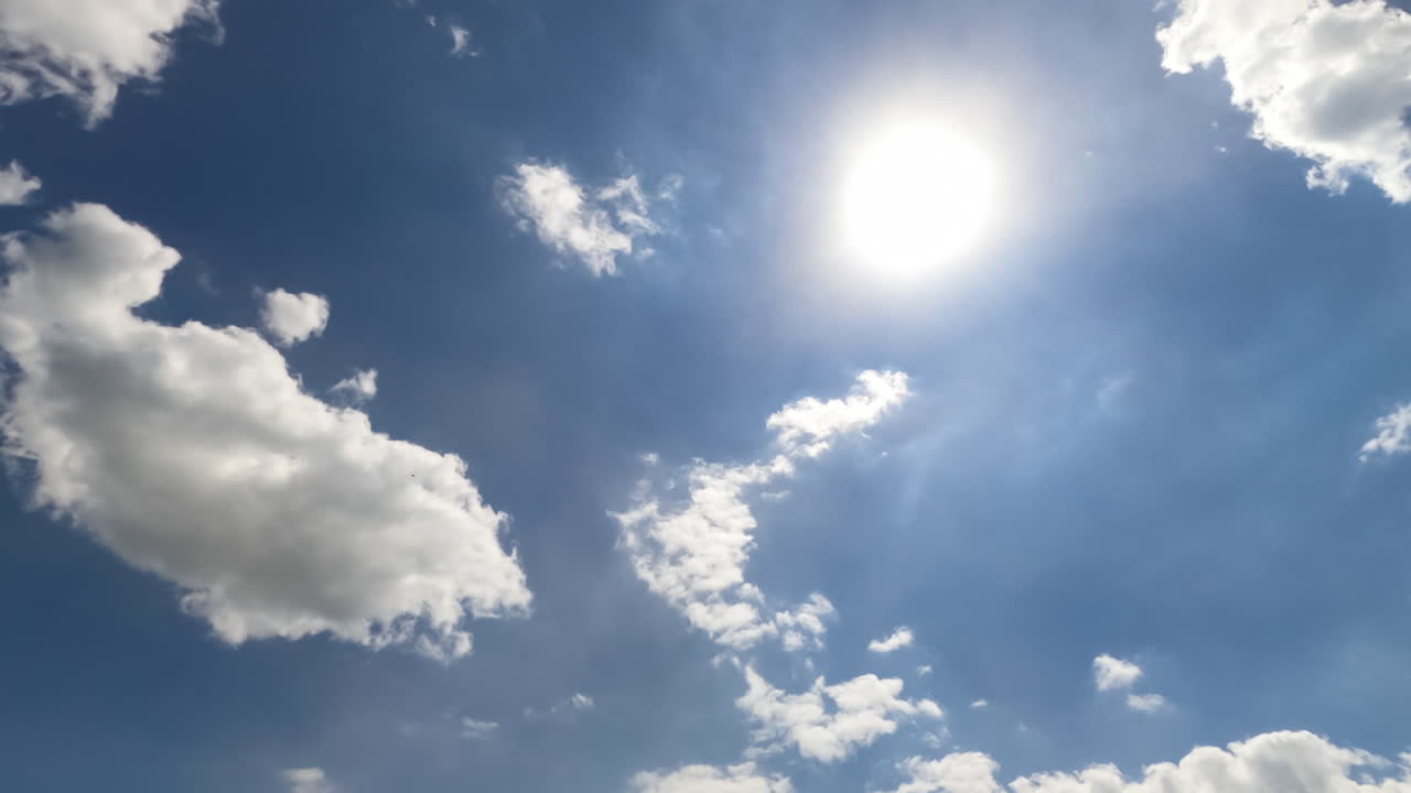 Bright sunny summer day sky with light clouds. Soft clouds covering sun from time to time. Timelapse. View from below.