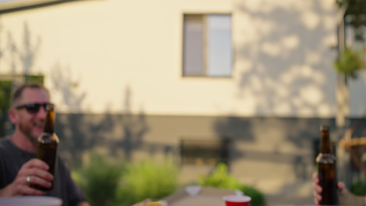 primer plano un grupo de jóvenes amigos sonando copas juntos en una mesa durante el almuerzo en el patio de una casa suburbana