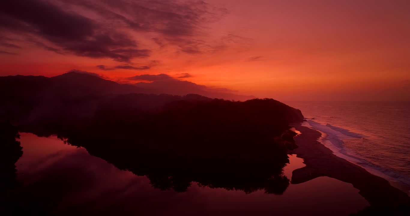 Lebendige, warme Sonnenuntergangsfarben über dem Fluss und der Küste des Tayrona Nationalparks. Luftaufnahme.