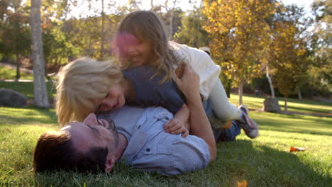 slow motion sequence of children jumping on father in park