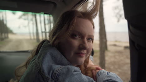 red haired female enjoys a drive through the countryside next to the lake