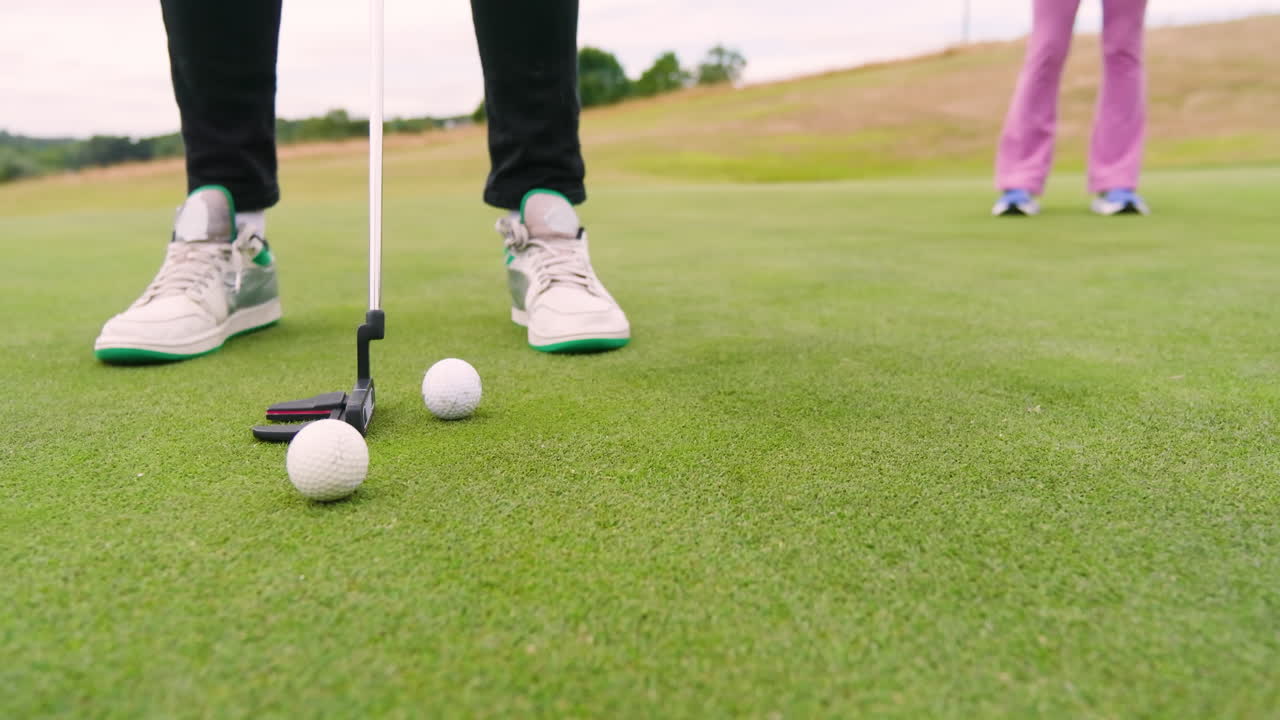 Two male and female golf players playing golf together, hitting balls with club on a golf course