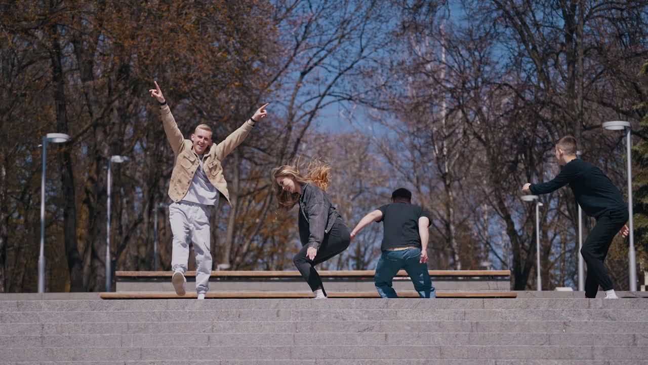 Friends running happily on the stairs outdoors. Positive young people having fun together in the city park. Friendship.