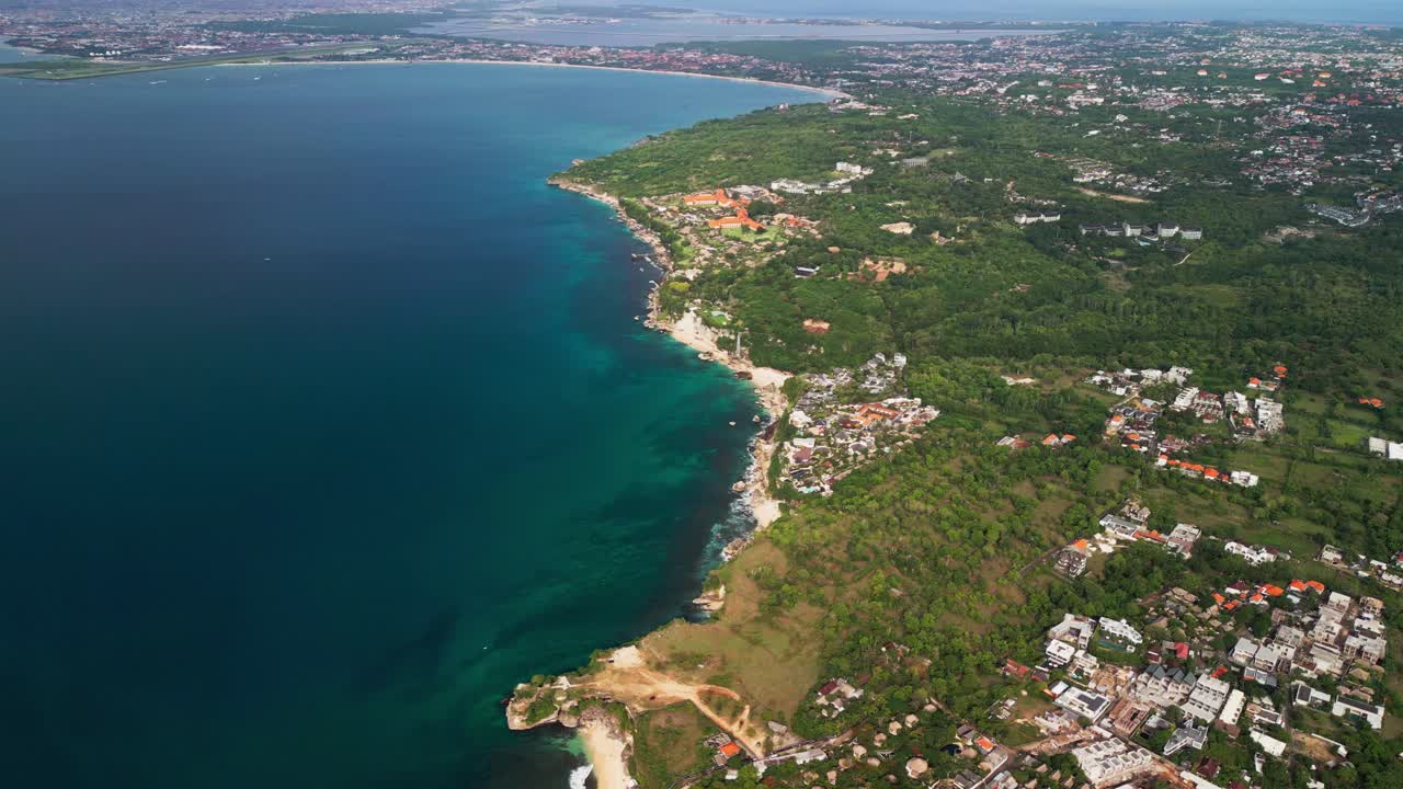 High altitude drone video capturing a long Indonesian coastline with rugged cliffs, turquoise water, and coral reef, revealing dramatic coastal terrain, clear ocean color, and natural shoreline