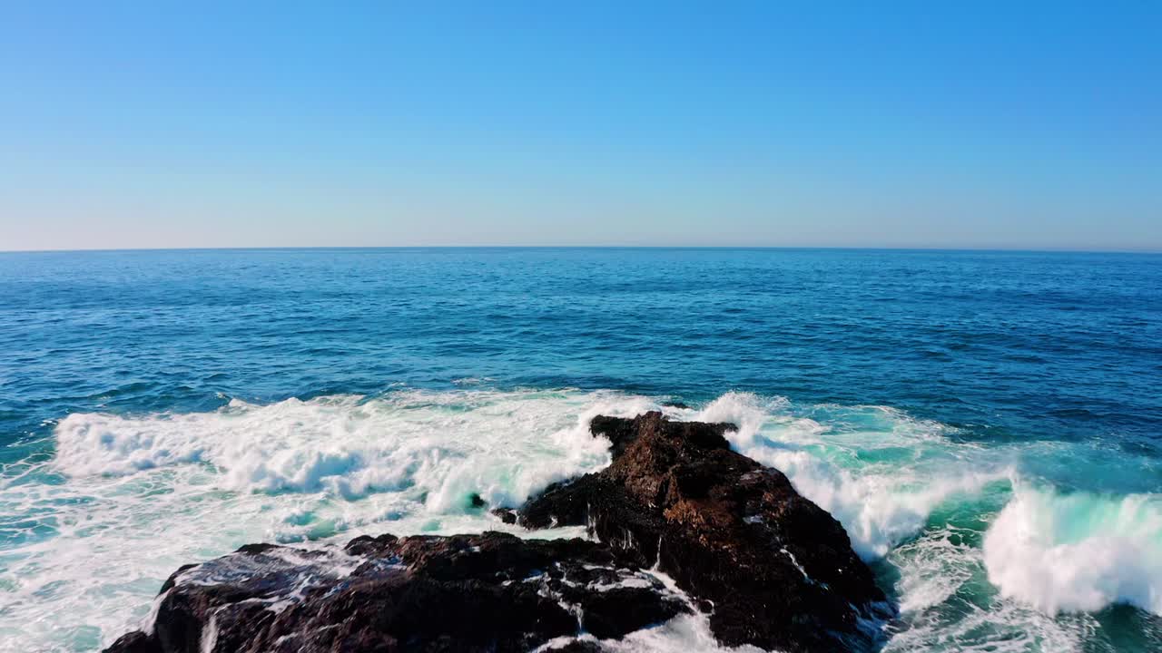 Waves crash against rocks in the middle of the ocean
