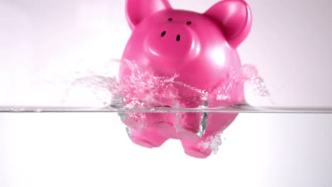 pink piggy bank falling in water