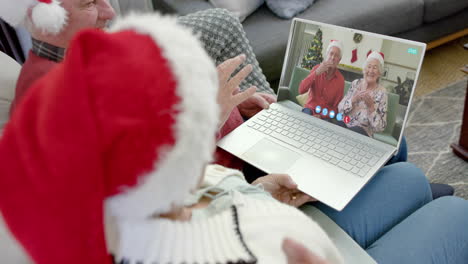 Dos-Felices-Parejas-Caucásicas-Mayores-Teniendo-Videollamada-Navideña-Con-Computadora-Portátil,-Cámara-Lenta