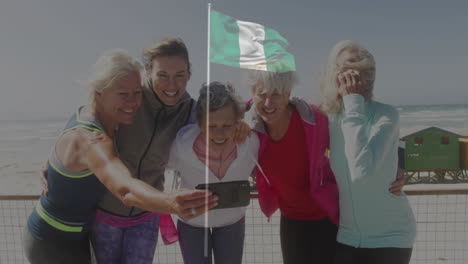 taking selfie with nigerian flag overlay, smiling women enjoying beach animation