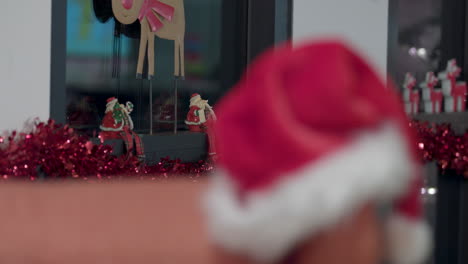 un sombrero de santa se sienta en la esquina de una silla y la decoración navideña y las luces llenan la habitación para las fiestas