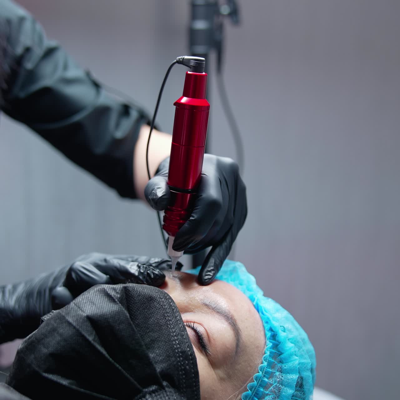 Pretty young woman making permanent beauty procedure. Cosmetic young specialist doing permanent make up