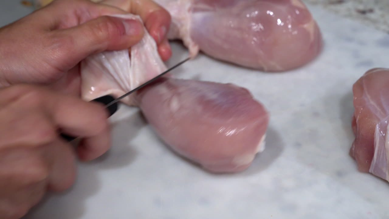 Rimozione della pelle da una coscia di pollo cruda