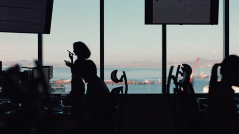 silhouette of business woman using smartphone having phone call chatting on mobile phone looking out window corporate executive discussing sales working late in busy office