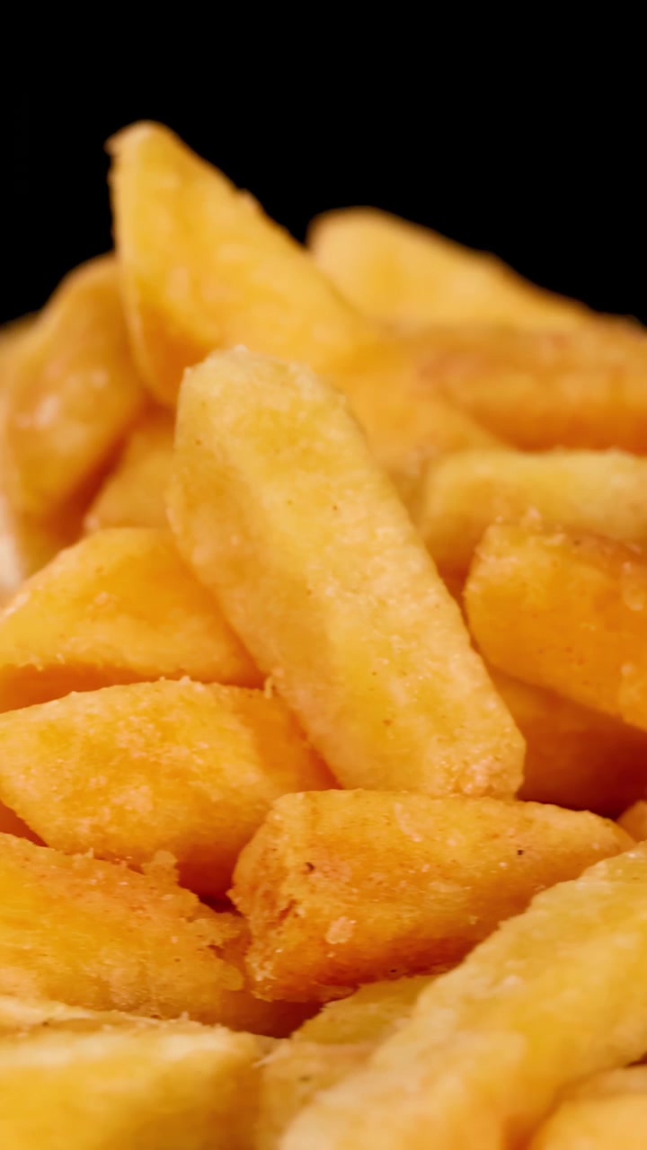 Patatas fritas doradas giran bajo una brillante iluminación de estudio, destacando su textura crujiente y su apetitoso detalle.