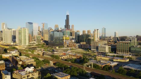 Die-Drohne-Fliegt-An-Der-Amerikanischen-Flagge-Und-Der-Chicago-Flagge-Vorbei,-Um-An-Klaren-Sommertagen-Die-Skyline-Von-Chicago-Zu-Enthüllen