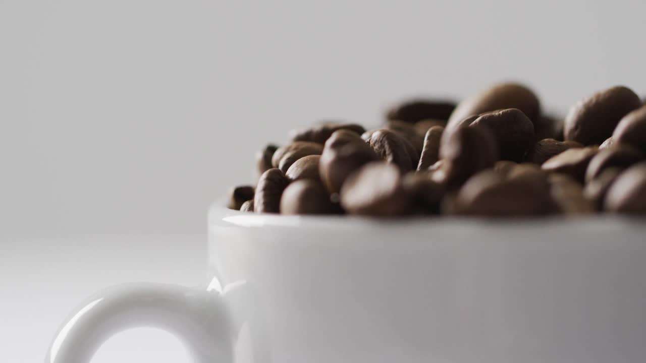 Video af kop med ristede brune kaffebønner på hvid baggrund