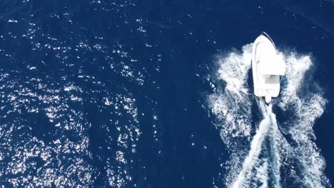 aerial top down view of luxury speed boat moving on blue ocean making waves