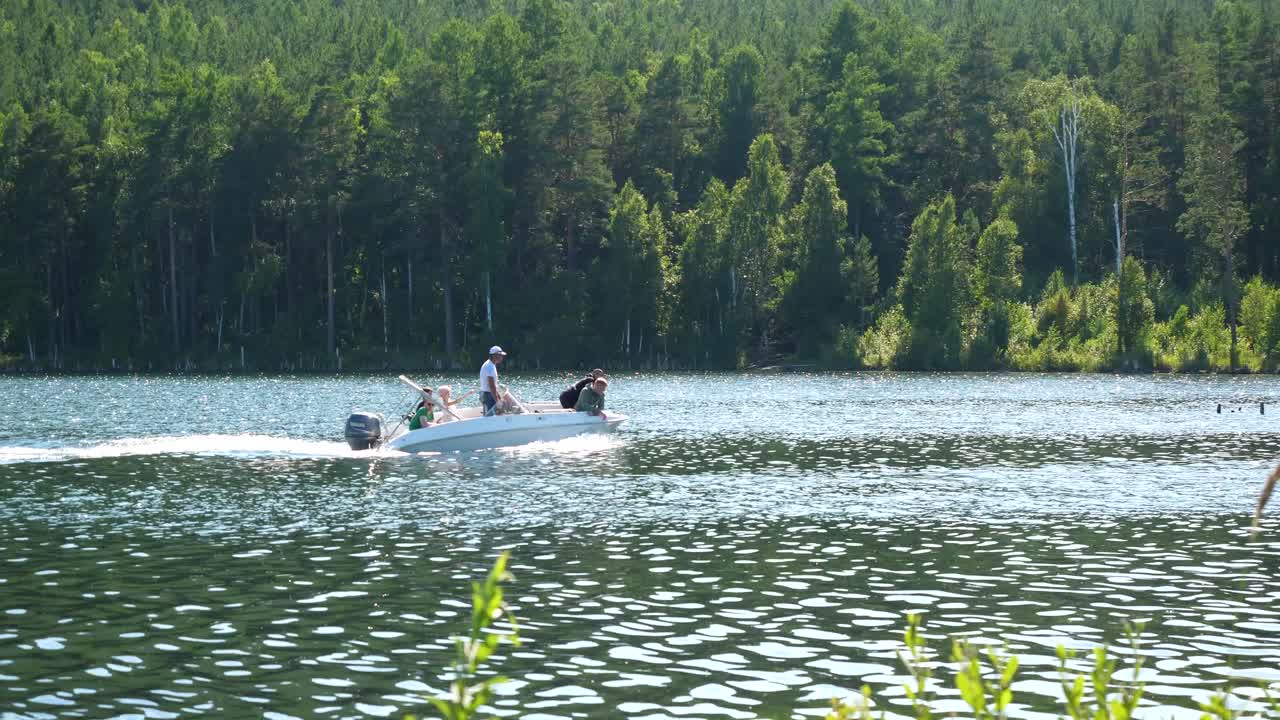 Люди на моторной лодке на озере, окруженном лесом