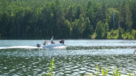 people on a motorboat on a lake surrounded by a forest