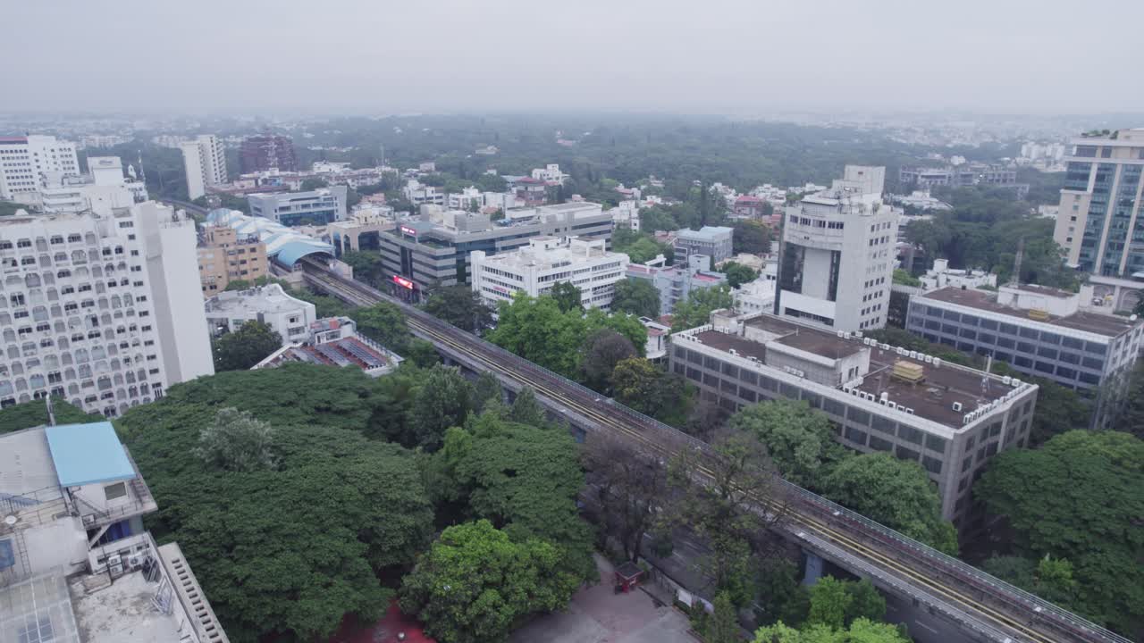 A View from above an office building of a rooftop terrace and metro train track Within those buildings and A residential apartment complex is located in the vicinity