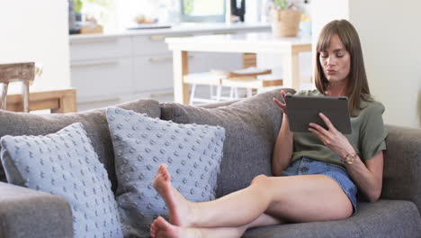 Middle-aged-Caucasian-woman-relaxes-on-a-sofa-at-home,-with-copy-space