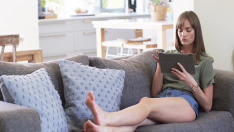mujer caucásica de mediana edad se relaja en un sofá en casa, con espacio para copiar
