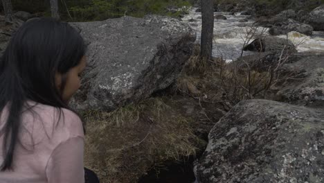 girl looking at the water on the riverside in the forest