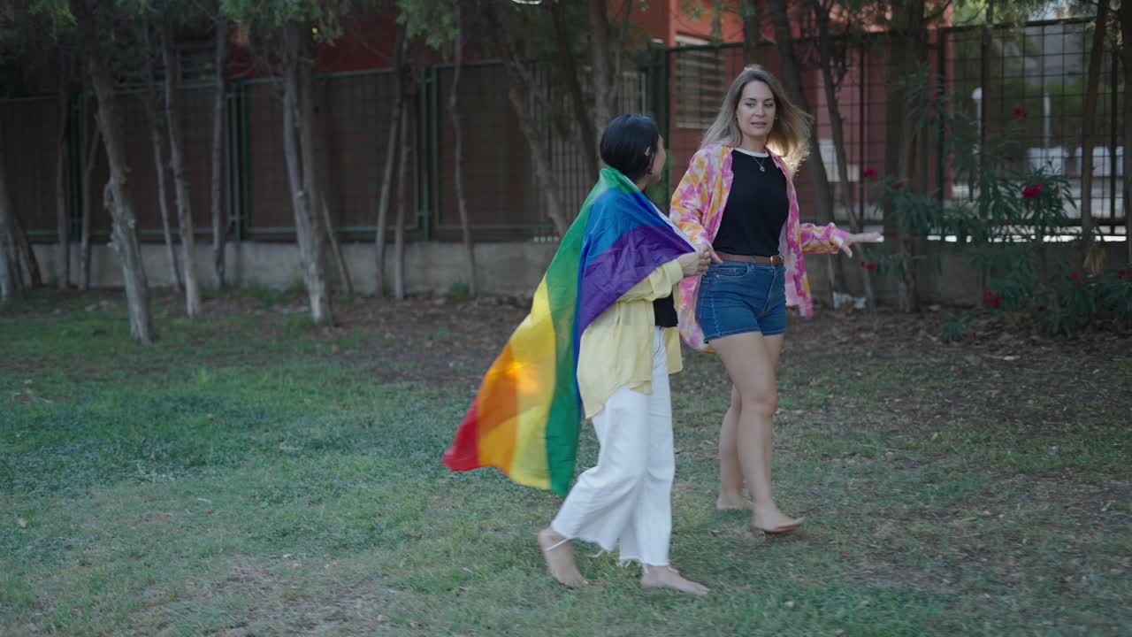 Two women walking with a rainbow pride flag