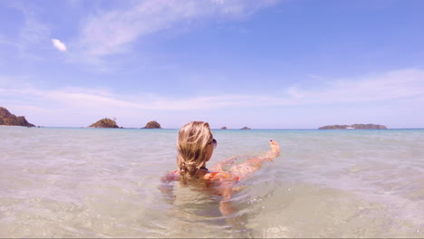 Young-Beautiful-Woman-sits-in-the-crystal-clear-oceans-of-Nacpan-Beach-in-El-Nido-Philippines,-perfect-holiday-and-dream-destination