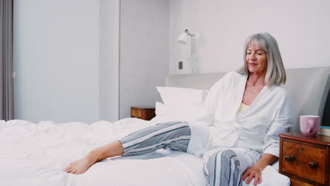 senior woman waking up and stretching in bedroom