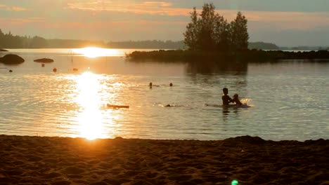 Familie-Hat-Spaß-Im-Wasser-Bei-Sonnenuntergang,-Verspielter-Vater-Wirft-Tochter-Herum,-Silhouetten-Mit-Wunderschönem-Bunten-Hintergrund