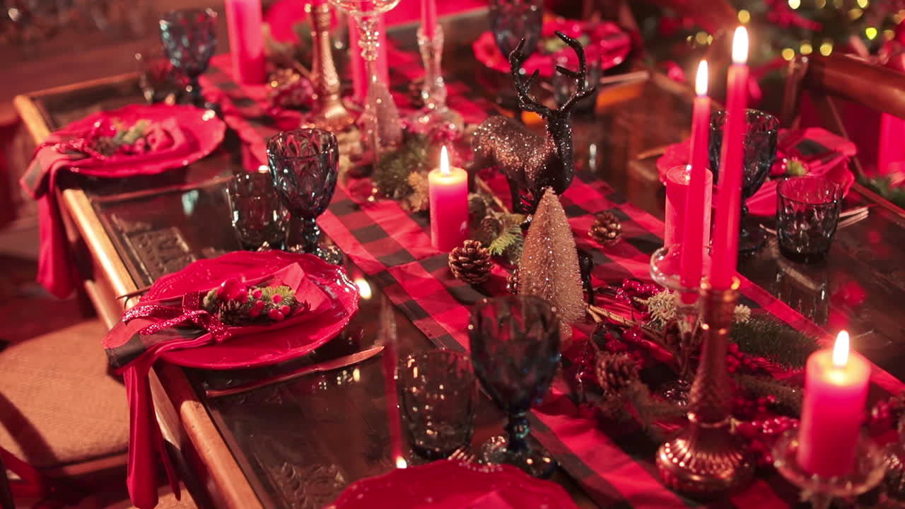 Red colors and shades in decoration of festive Christmas dinner table. Shining decorations and lights on the table for celebrating New Year. View from above.