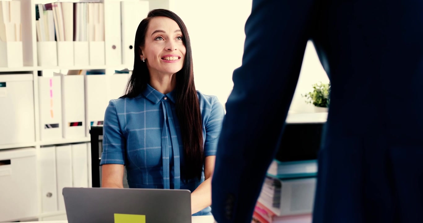 Un professionista sorride davanti a un laptop in un ufficio moderno che promuove la produttività e la collaborazione