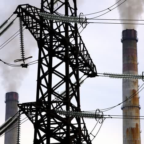 dark factory pipes against electrical pylons. factory pipes with smoke. dirty smoke pours out of chimneys into the air. aerial view video