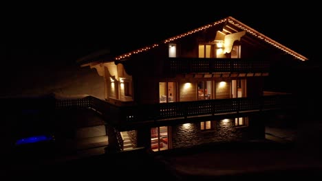 Dolly-out-from-balcony-of-beautiful-chalet-in-winter-at-night