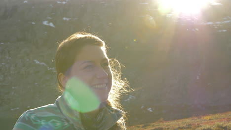 close up of a woman smiling and lauging while on a sunset hike on a mountain in norway, slow motion with lens flares